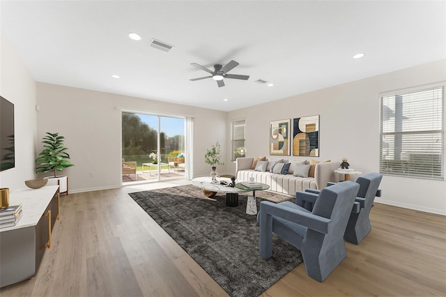 living area featuring light wood-style floors, ceiling fan, baseboards, and visible vents