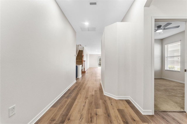 hallway featuring visible vents, baseboards, and wood finished floors