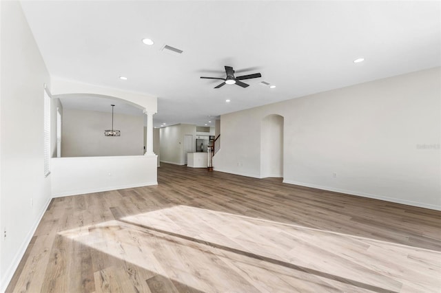 unfurnished living room with arched walkways, wood finished floors, visible vents, and recessed lighting
