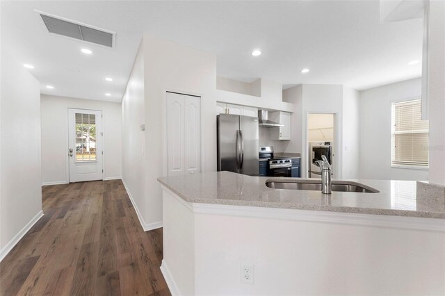 kitchen with visible vents, wall chimney exhaust hood, a sink, dark wood-style flooring, and appliances with stainless steel finishes