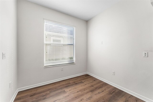 spare room with baseboards and wood finished floors