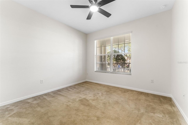 carpeted spare room with baseboards and a ceiling fan
