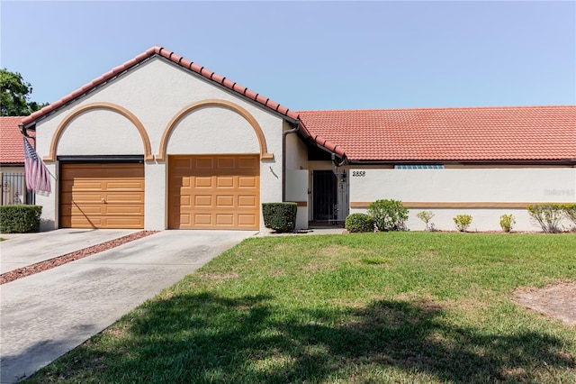 mediterranean / spanish home featuring a tile roof, concrete driveway, an attached garage, a front yard, and stucco siding