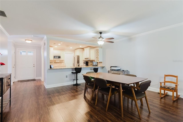 dining room with baseboards, a ceiling fan, dark wood-style flooring, and crown molding