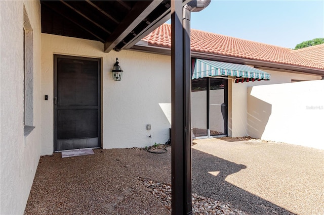 exterior space with stucco siding, a patio, and a tiled roof