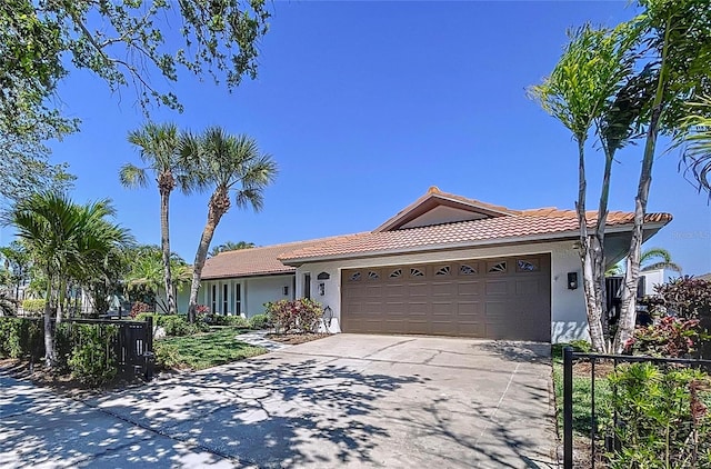 773 Snug Is, Clearwater Beach, FL 33767 - ranch-style home with a tiled roof, a garage, stucco siding, concrete driveway, and fence