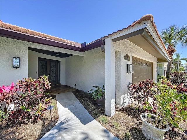 773 Snug Is, Clearwater Beach, FL 33767 - entrance to property featuring an attached garage, stucco siding, and a tiled roof