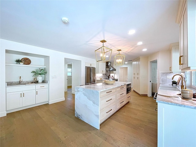 773 Snug Is, Clearwater Beach, FL 33767 - kitchen featuring appliances with stainless steel finishes, wall chimney range hood, a kitchen island, light wood finished floors, and recessed lighting