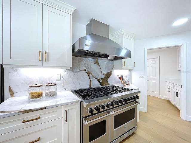 773 Snug Is, Clearwater Beach, FL 33767 - kitchen with range with two ovens, wall chimney exhaust hood, white cabinets, light wood-style flooring, and tasteful backsplash
