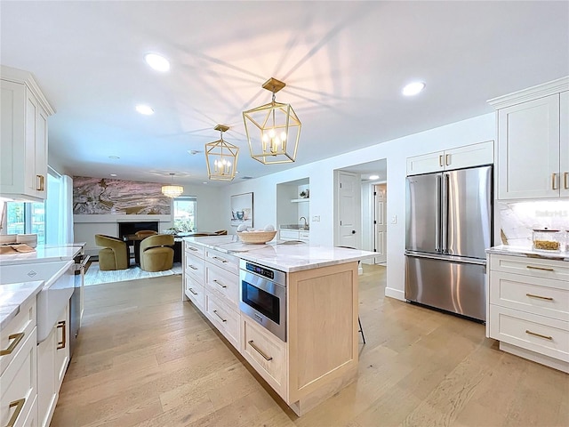 773 Snug Is, Clearwater Beach, FL 33767 - kitchen with stainless steel fridge, light wood finished floors, light stone counters, white cabinets, and recessed lighting