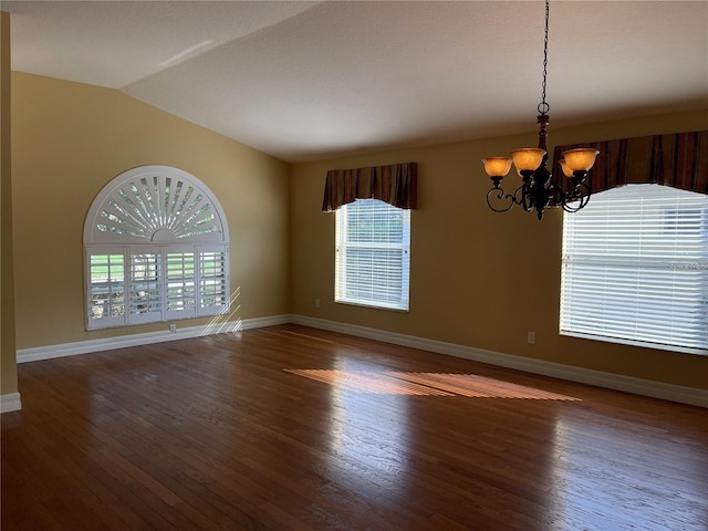 unfurnished room with a healthy amount of sunlight, lofted ceiling, wood finished floors, and a notable chandelier