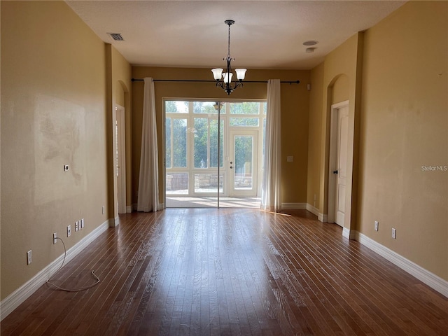 spare room with baseboards, visible vents, dark wood-style floors, and a chandelier