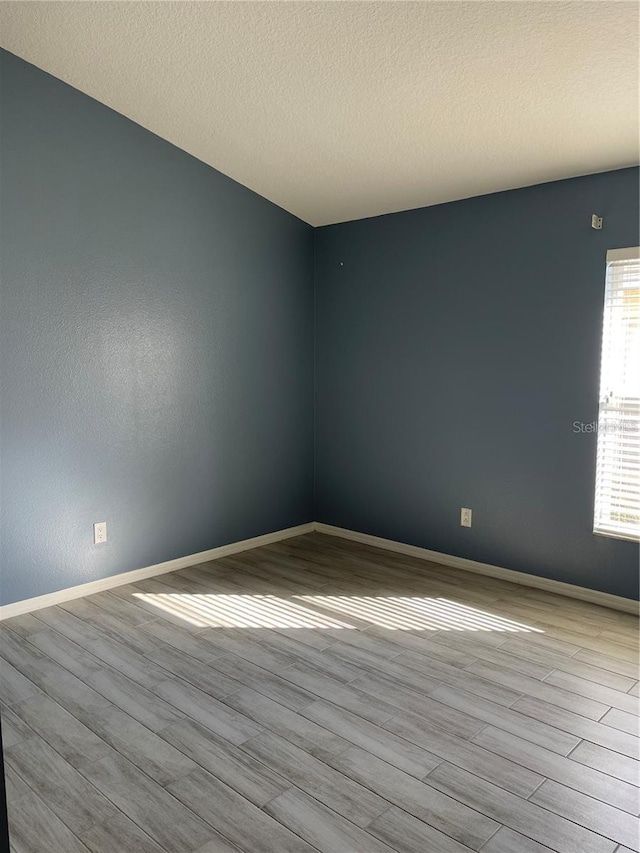 spare room with baseboards and wood finished floors