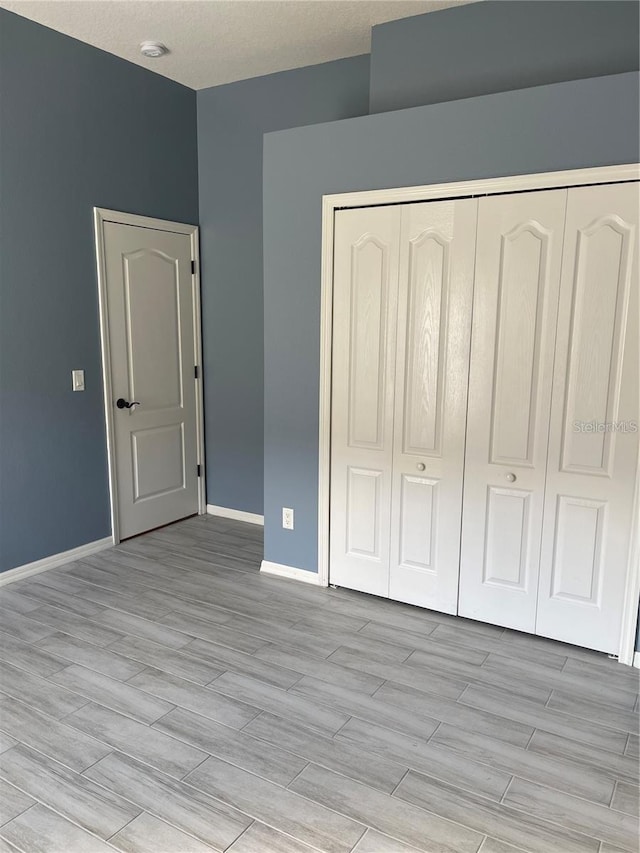 unfurnished bedroom with baseboards, a closet, and light wood finished floors