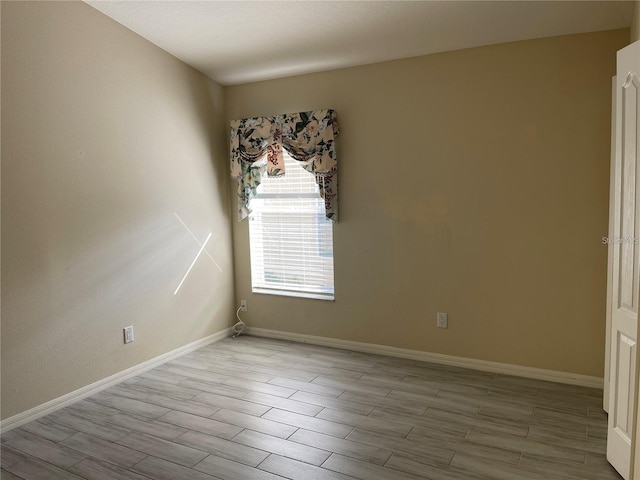 spare room featuring baseboards and wood finished floors