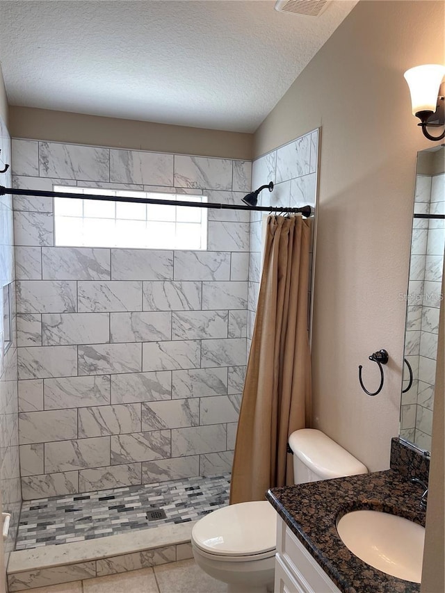 full bath with vanity, toilet, a textured ceiling, and a stall shower