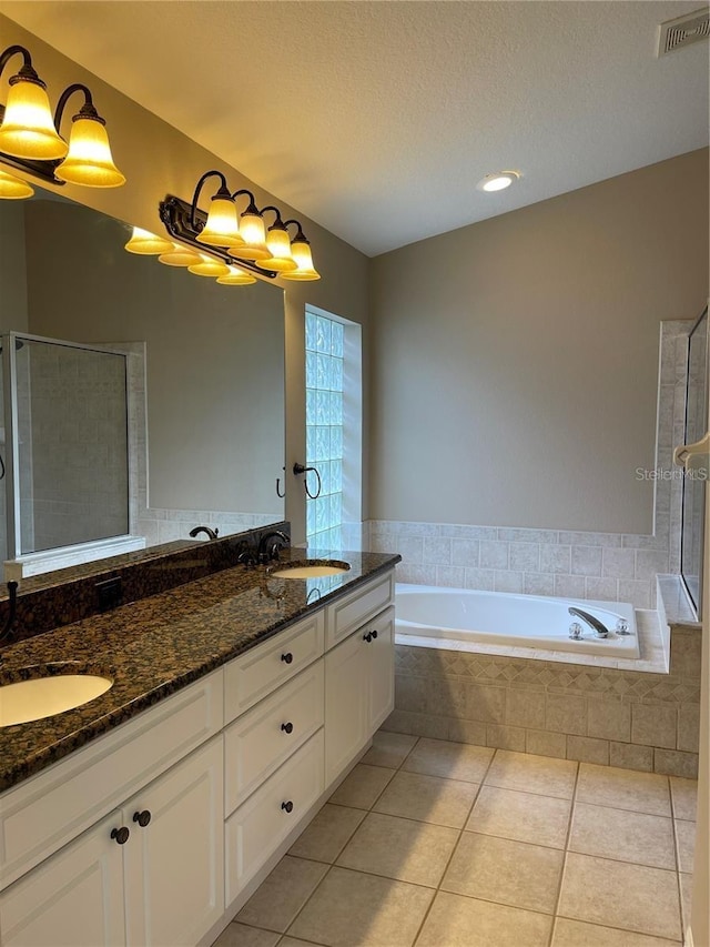 bathroom with a sink, tile patterned flooring, double vanity, visible vents, and a garden tub