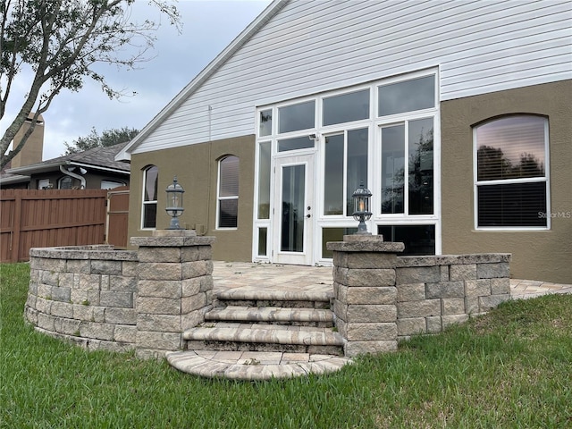 rear view of property featuring fence, a patio area, and stucco siding