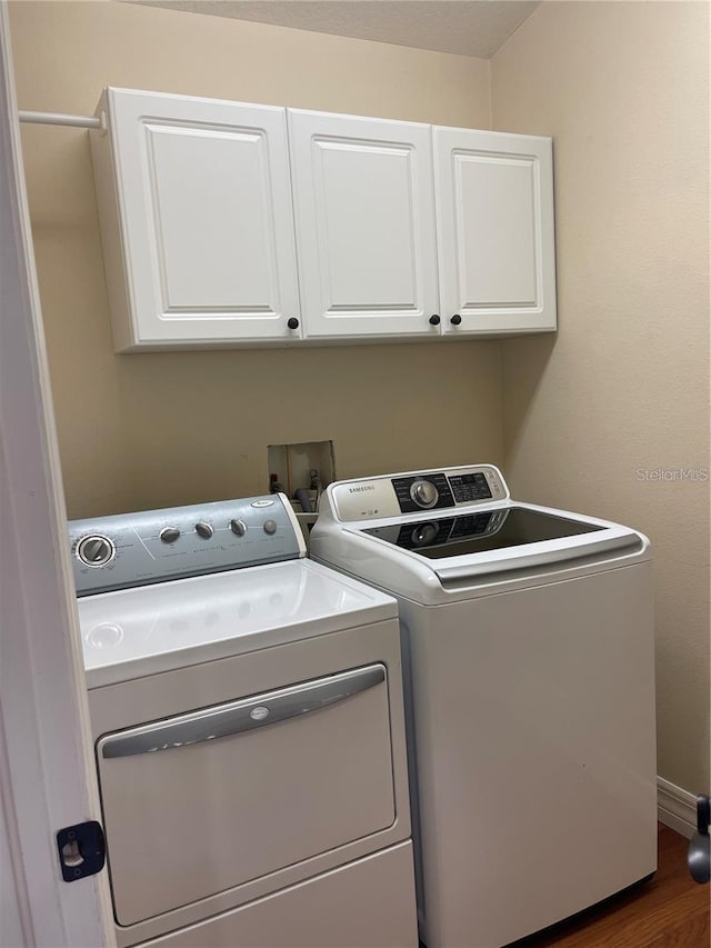 laundry room featuring wood finished floors, cabinet space, and washing machine and dryer