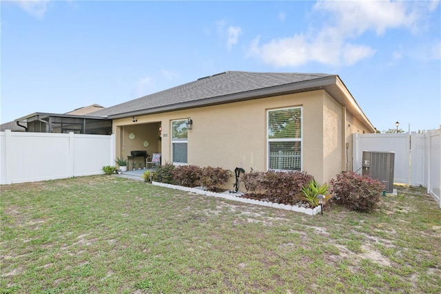 8975 Southern Charm Cir, Brooksville, FL 34613 - rear view of property with fence, cooling unit, roof with shingles, stucco siding, and a yard