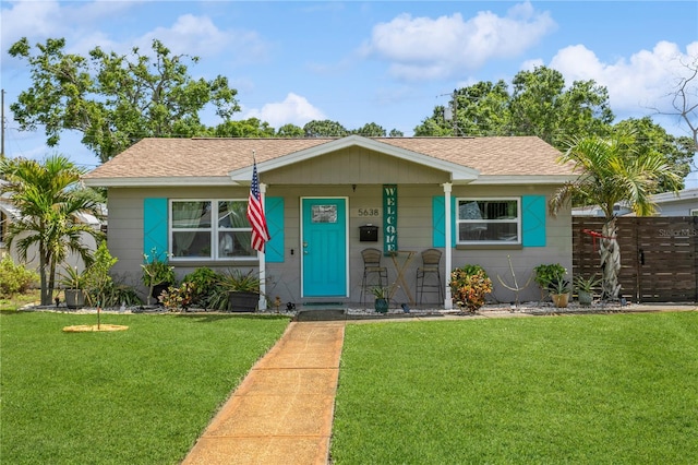 view of front of house featuring a front yard, fence, and roof with shingles