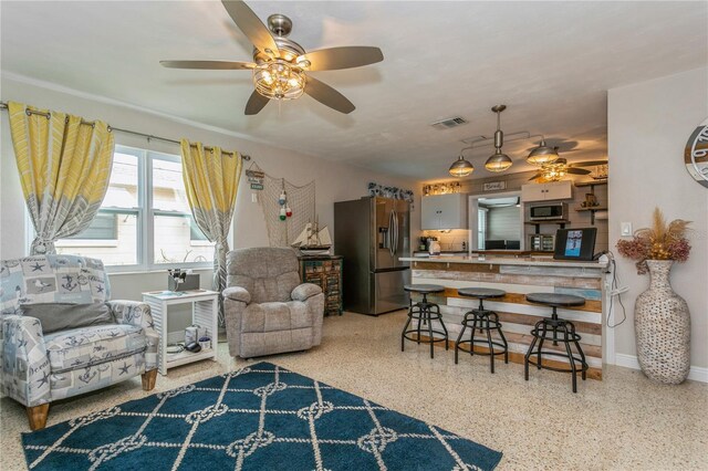 living room featuring visible vents, baseboards, a ceiling fan, and speckled floor