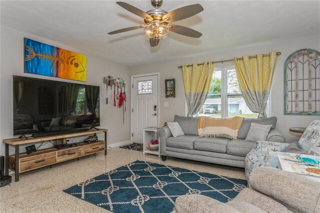 living room featuring baseboards, speckled floor, and a ceiling fan
