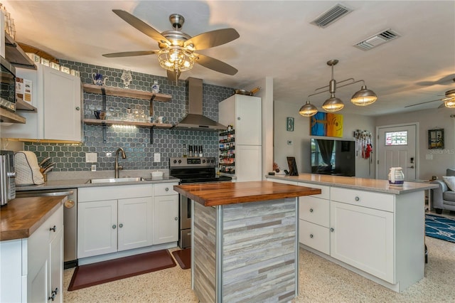 kitchen with stainless steel appliances, wood counters, wall chimney exhaust hood, and a sink