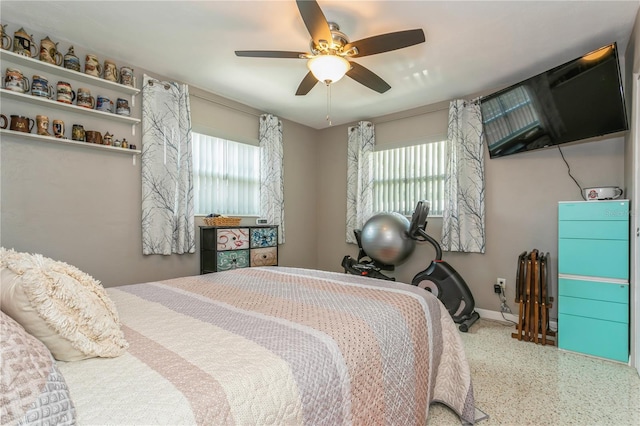 bedroom with speckled floor, ceiling fan, multiple windows, and baseboards