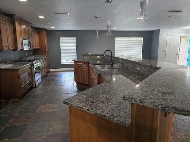 kitchen featuring stainless steel appliances, plenty of natural light, stone tile floors, and a sink