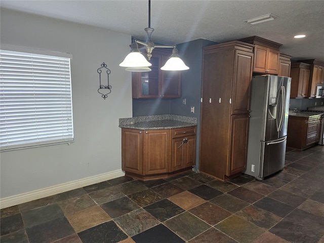 kitchen featuring stainless steel appliances, stone tile floors, plenty of natural light, and baseboards