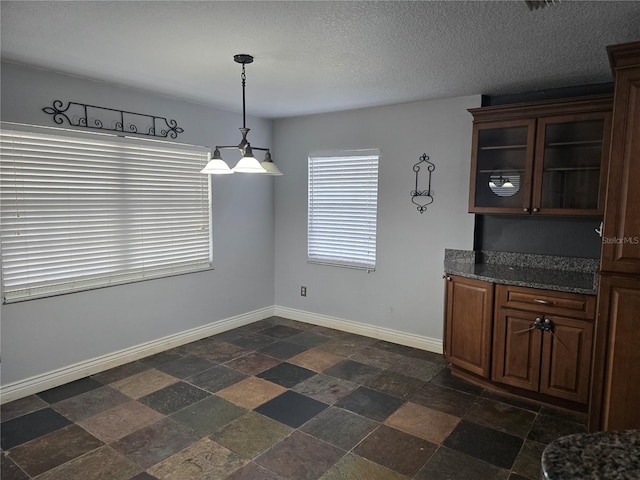 unfurnished dining area featuring stone finish floor and baseboards
