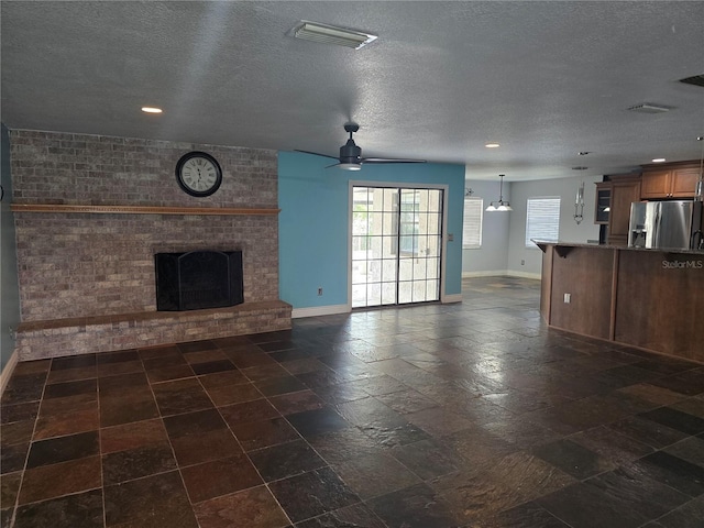 unfurnished living room featuring visible vents, baseboards, a textured ceiling, and a fireplace