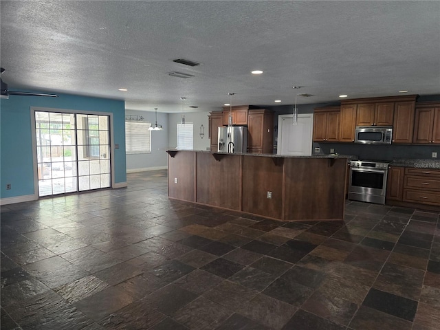 kitchen featuring stainless steel appliances, recessed lighting, stone tile floors, and baseboards