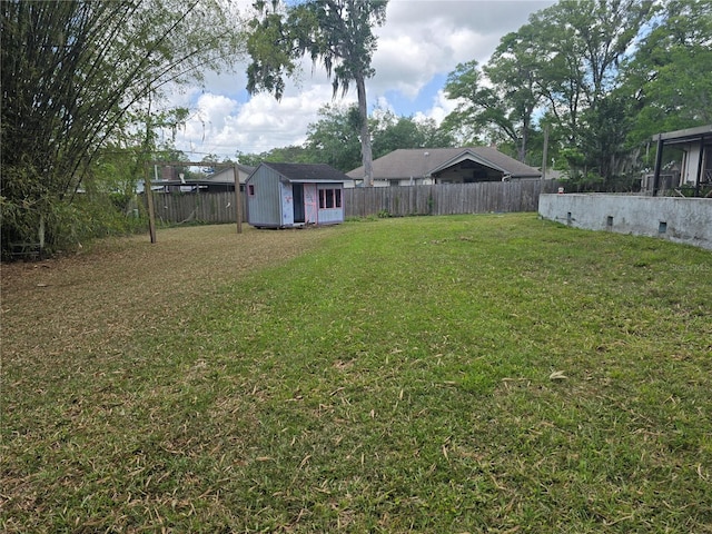 view of yard featuring an outbuilding, a fenced backyard, and a storage unit