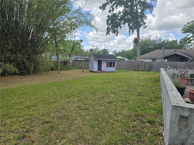 view of yard with a shed, a fenced backyard, and an outdoor structure