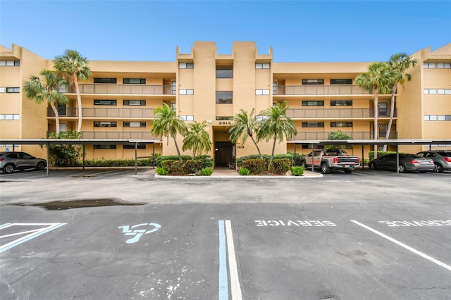 view of building exterior with covered and uncovered parking