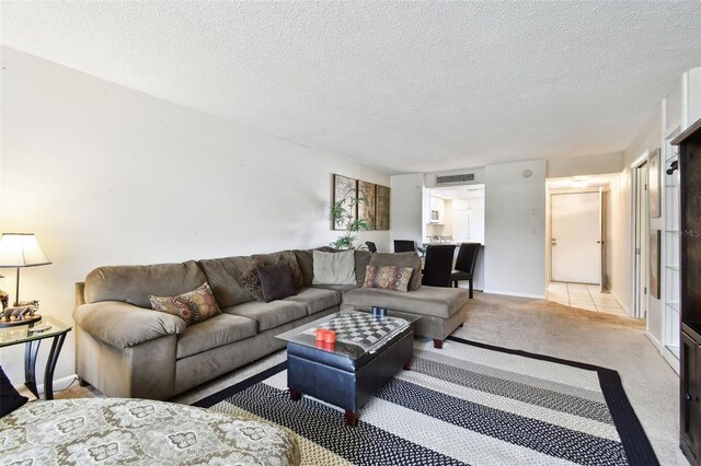 living area with visible vents, baseboards, light colored carpet, and a textured ceiling