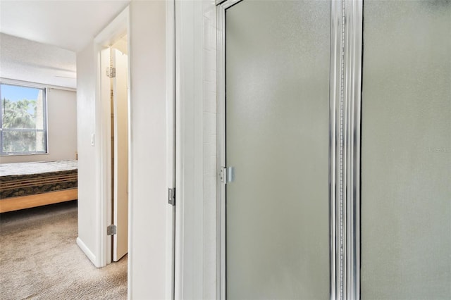 hallway featuring light colored carpet and baseboards