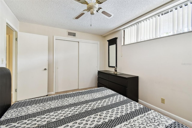 carpeted bedroom with ceiling fan, a textured ceiling, a closet, visible vents, and baseboards