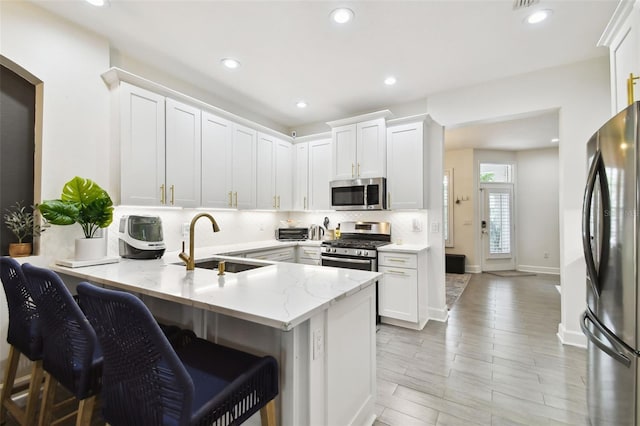 10011 Parley Dr, Tampa, FL 33626 - kitchen with tasteful backsplash, white cabinets, a sink, appliances with stainless steel finishes, and a peninsula
