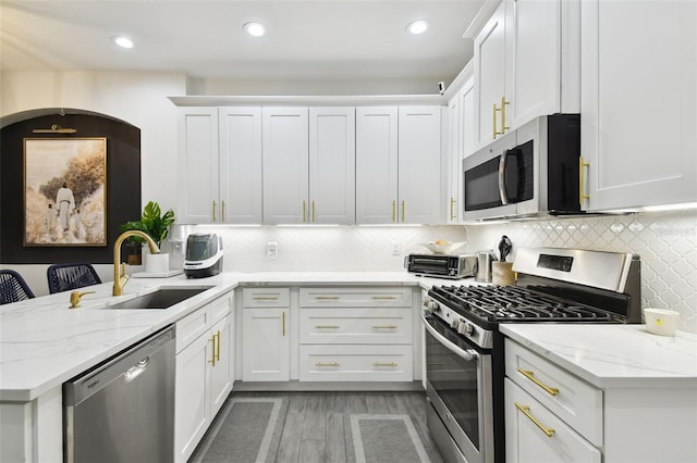 10011 Parley Dr, Tampa, FL 33626 - kitchen featuring a peninsula, white cabinetry, light stone countertops, appliances with stainless steel finishes, and a sink