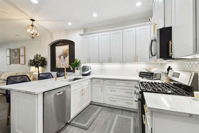 10011 Parley Dr, Tampa, FL 33626 - kitchen with white cabinets, a sink, a peninsula, recessed lighting, and stainless steel appliances