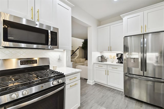 10011 Parley Dr, Tampa, FL 33626 - kitchen with tasteful backsplash, white cabinets, light wood-type flooring, appliances with stainless steel finishes, and light stone countertops