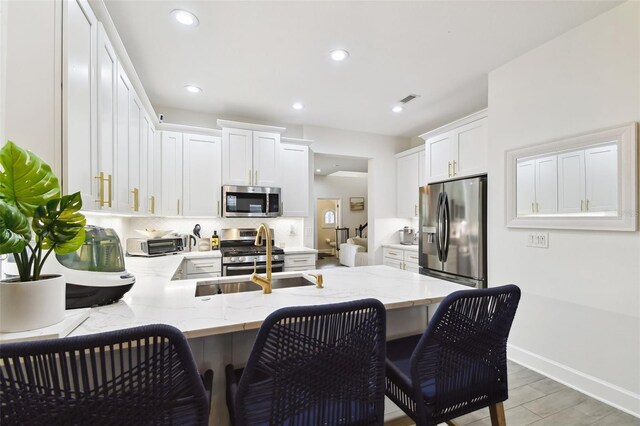10011 Parley Dr, Tampa, FL 33626 - kitchen with a peninsula, white cabinets, light stone counters, a sink, and stainless steel appliances