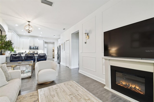 10011 Parley Dr, Tampa, FL 33626 - living room with a glass covered fireplace, an inviting chandelier, recessed lighting, visible vents, and wood finished floors