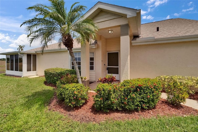 property entrance with a shingled roof, stucco siding, and a yard