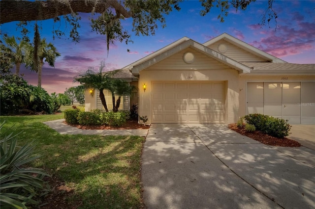 view of front of house featuring an attached garage, stucco siding, a front yard, and concrete driveway