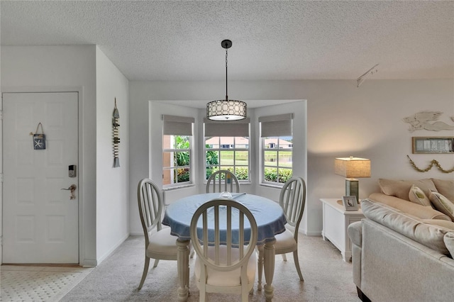 dining area featuring a textured ceiling, light carpet, and baseboards