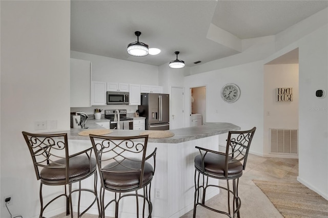 kitchen featuring a kitchen breakfast bar, visible vents, white cabinets, a peninsula, and stainless steel appliances